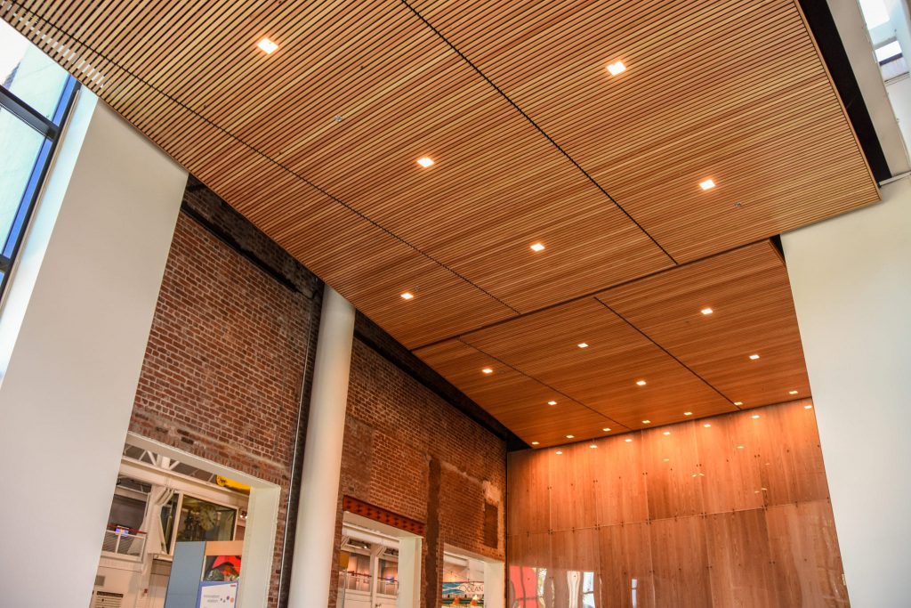 Panel sizes matter when shopping for wood ceilings. By sticking with standard sizes, linear wood ceilings like this one can remain cost effective.