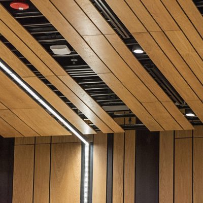 9Wood's 2100 Panelized Linear at the Hyatt Regency Seattle in Seattle, Washington. LMN Architects. The wood panels are assembled with black, shiplap backers each 12 in. o.c. The suspension uses hanger wires to attach 15/16 in. heavy-duty t-bar grid directly to the structure above.