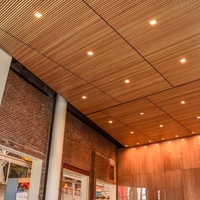 Panel sizes matter when shopping for wood ceilings. By sticking with standard sizes, linear wood ceilings like this one can remain cost effective.