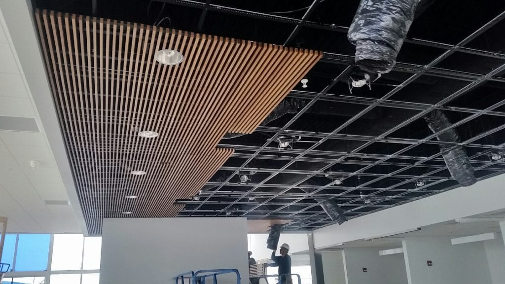 this picture shows a wood ceiling partially installed across an entire suspended tbar grid system.