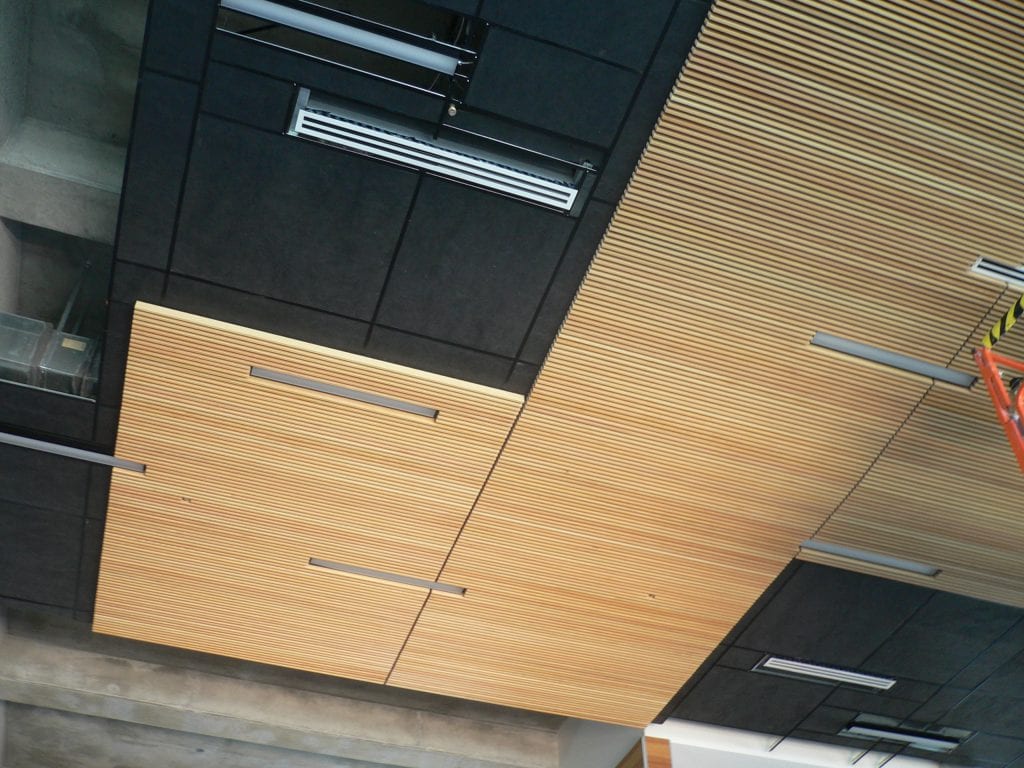 Rigid faced fiberglass panels installed above a wood grille ceiling