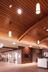 http://The%209Wood%208200%20Linear%20Wood%20Wave%20in%20Cherry%20Plain%20Sliced%20Veneer%20with%20Walnut%20Stain%20in%20a%20lobby%20setting%20with%20integrating%20lighting.